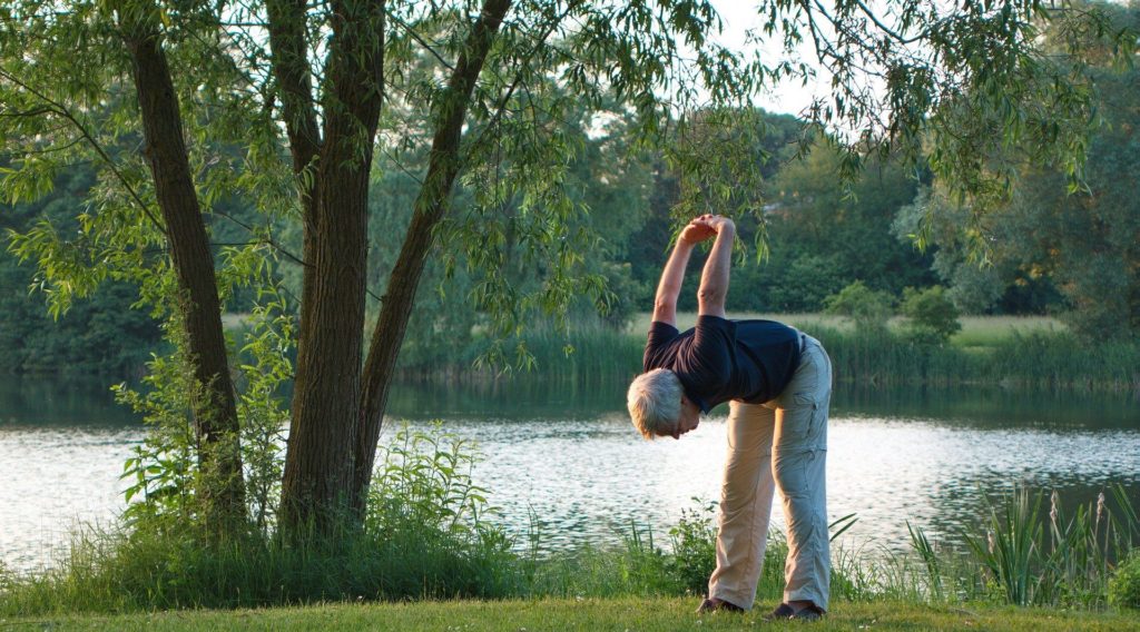 Mann macht Yoga vor einem See